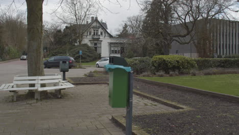 garbage bin in small park with trash bag in the wind