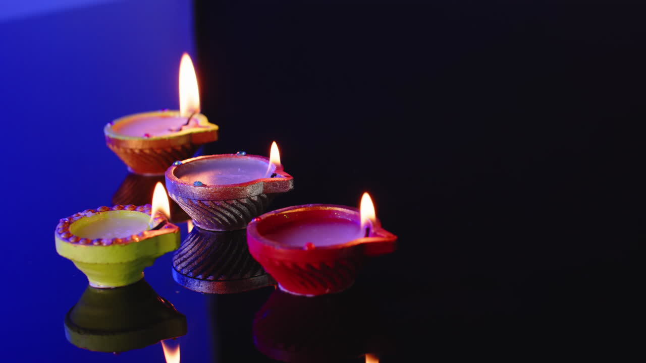 Primo piano di candele accese in fila che celebrano il Diwali su sfondo blu, con spazio per il testo