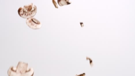 Sliced-mushroom-pieces-falling-in-slow-motion-on-white-studio-backdrop-in-4k