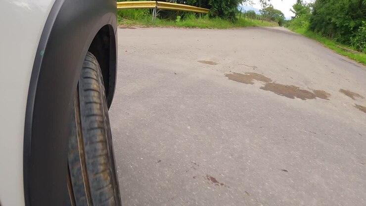 slow motion close up of a white car tire navigating a curve on a paved road. Dramatic low angle shot suitable for investigative or safety themes