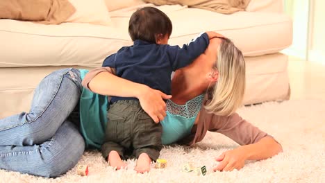 mujer jugando con su bebé acostada en una alfombra