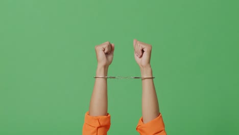 close up of male prisoner's hands in handcuffs being raised on the green screen background