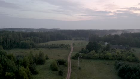 Drone-flight-over-a-country-road-during-a-foggy-sunset