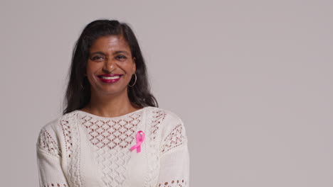 studio portrait of smiling mature woman wearing pink breast cancer awareness ribbon against white background 3