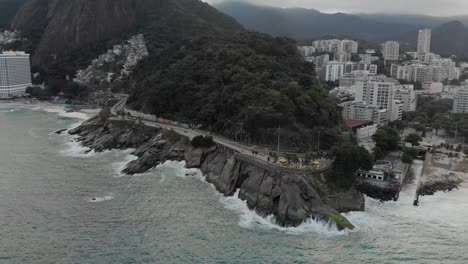 enfoque aéreo en el mirador de leblon y estacionamiento con olas rompiendo en la costa rocosa en un día gris nublado en río de janeiro