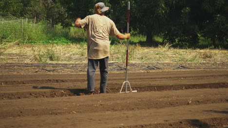 contadino che livella il campo con uno strumento manuale, persona di campagna reale che lavora all'aperto durante una giornata di sole