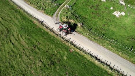 tractor rojo conduciendo por un camino de ripio en un entorno rural
