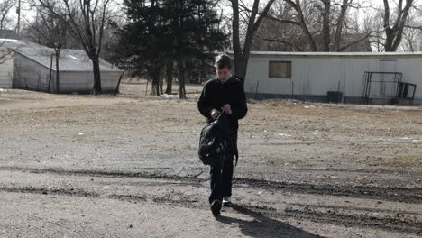 A-young-high-school-aged-teen-boy-walks-outside-with-backpack-on-his-way-to-school