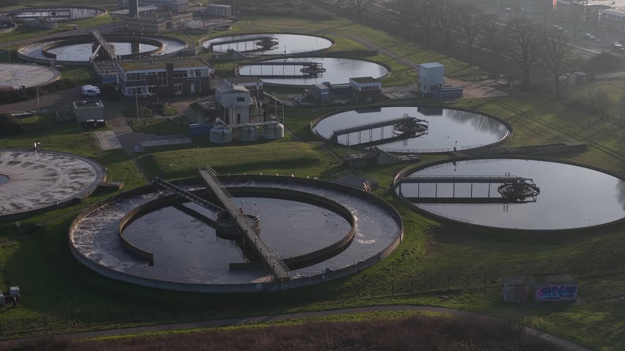 Aerial drone video of a wastewater and sewage treatment plant in Haarlem, Netherlands, showing water purification infrastructure, circular basins, environmental management, and urban sanitation system