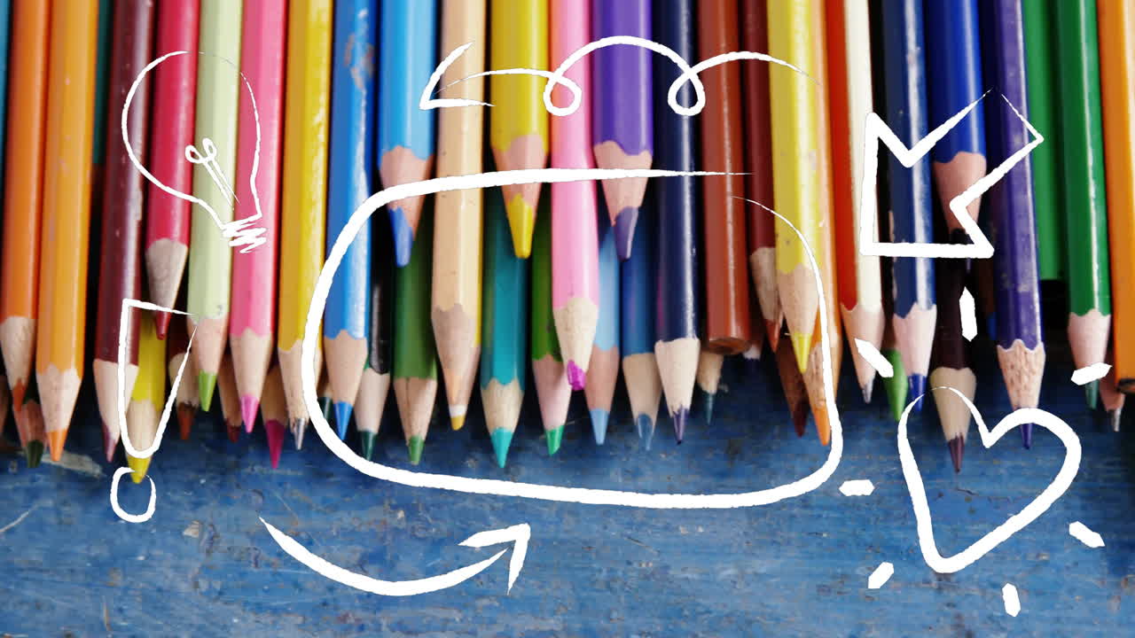 Colored pencils lining up on worn blue wooden board, showing white doodles circling tips