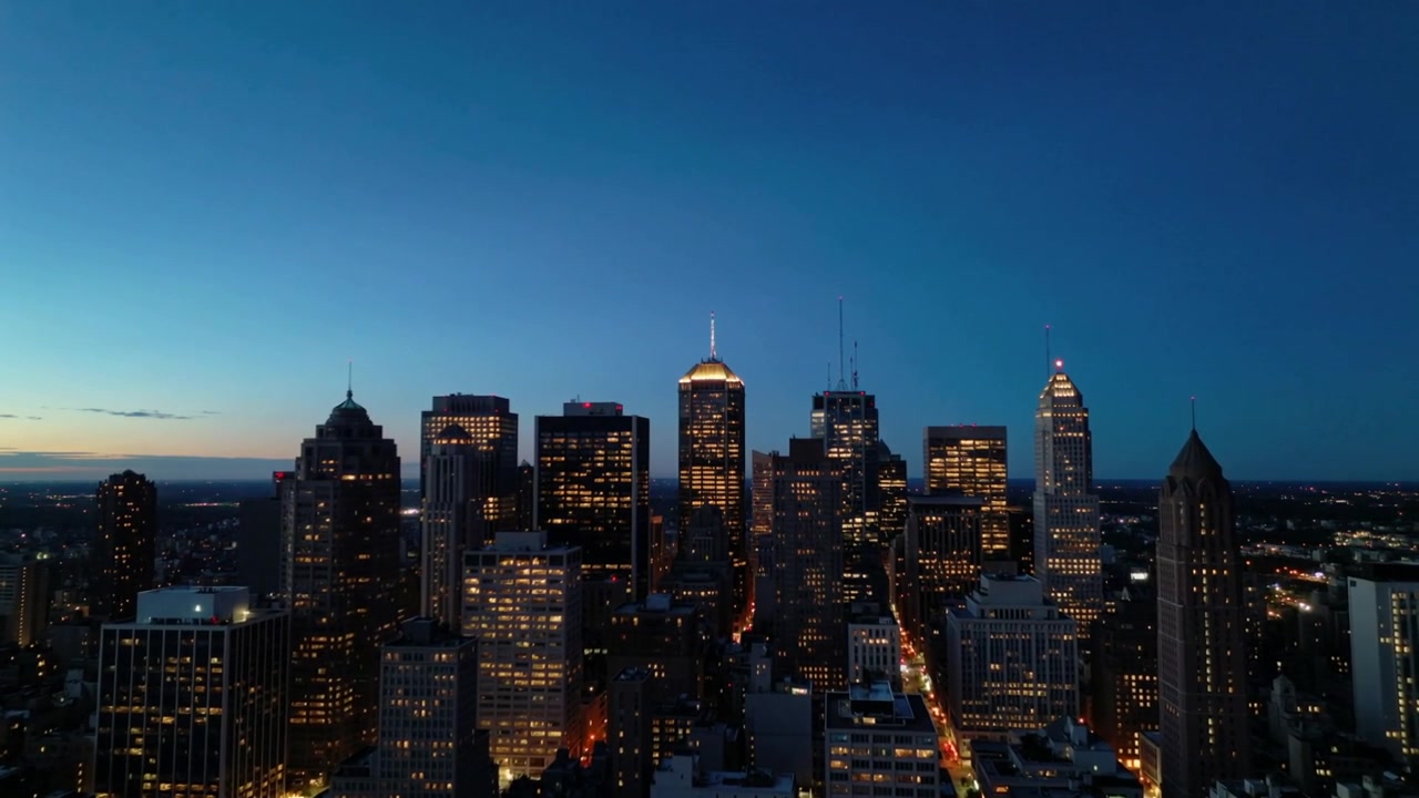 Mostrando lo skyline di grattacieli che si oscura con il crepuscolo che si intensifica sul centro città, con viale e finestre illuminate.
