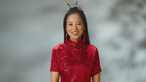 Portrait-shot-of-Asian-young-cheerful-woman-in-red-traditional-clothes-smiling-at-camera