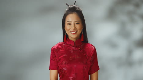 portrait shot of asian young cheerful woman in red traditional clothes smiling at camera