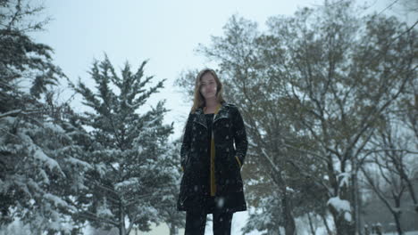 happy woman outside in slow motion winter snow as snowflakes fall in cinematic slow motion