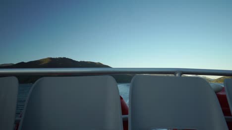 asientos de barco vacíos durante el crucero matutino al amanecer en el sonido de la reina charlotte, nueva zelanda con montañas en el fondo
