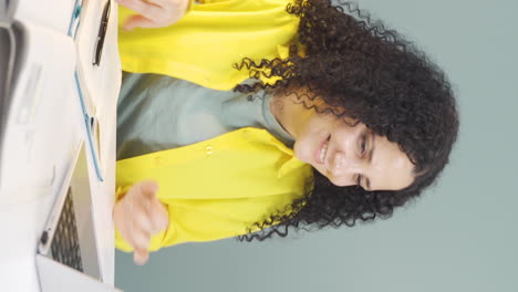 video vertical de una mujer joven trabajando en una computadora portátil con una expresión feliz.