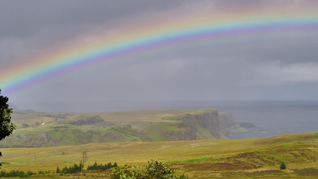 arco iris sobre prados y acantilados en la isla de skye en escocia con nubes