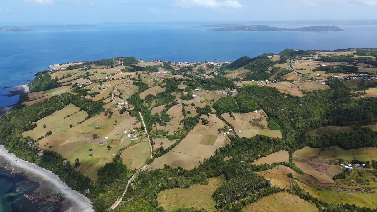 Aerial perspective of Lemuy Island in the Chiloe Archipelago, Chile, showcasing its patchwork of fields, coastline, and lush vegetation