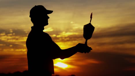 sunset silhouette successful male golfer holding winning trophy