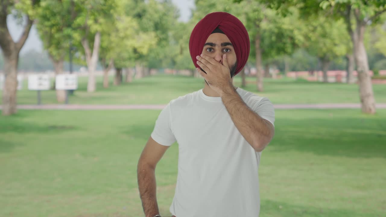 Uomo indiano Sikh vede una notizia scioccante al parco.