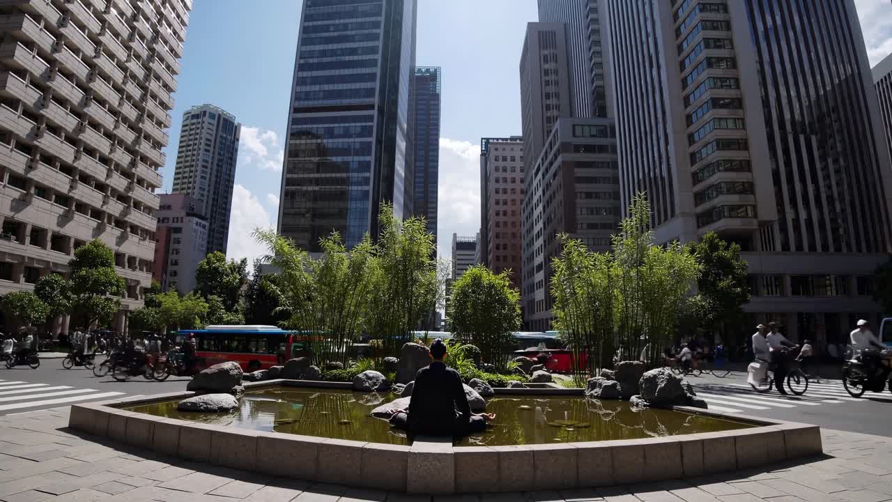 Un individuo sentado junto a un estanque tranquilo en un entorno urbano, rodeado de imponentes edificios y vegetación vibrante, capturando la esencia de la vida en la ciudad y la armonía de la naturaleza.