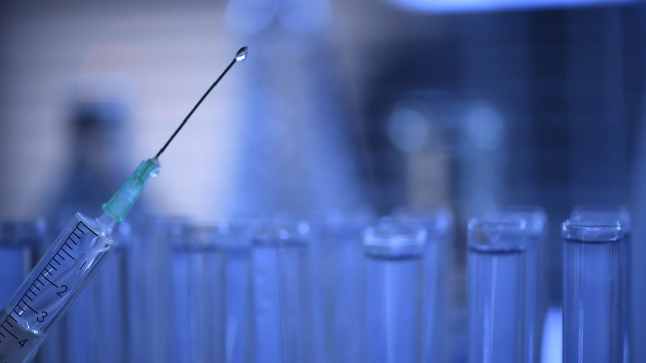 Siringa medica che espelle gocce di liquido in un laboratorio