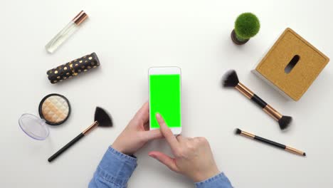 top view overhead of woman using smartphone by beauty products