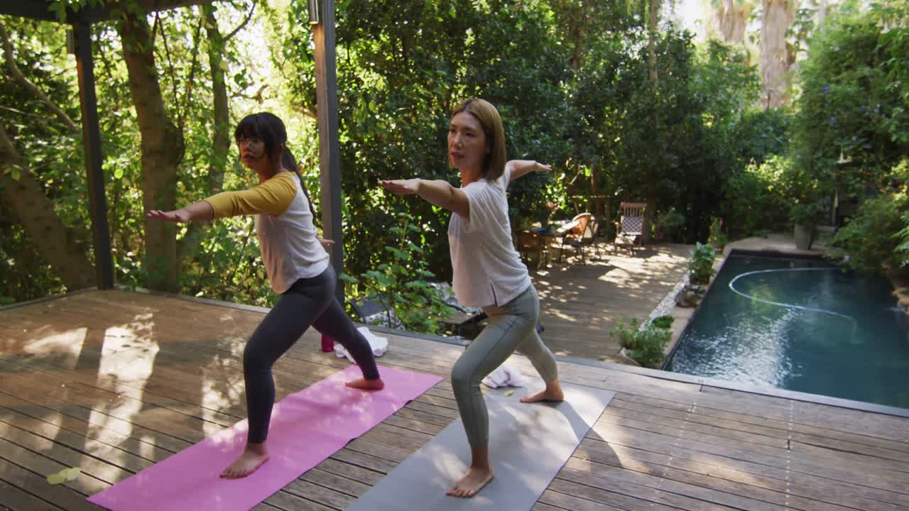 madre y hija asiáticas practicando yoga al aire libre en el jardín