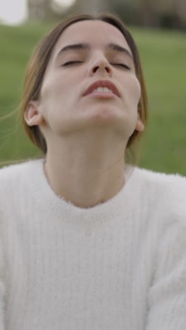 a young woman with closed eyes in a serene outdoor setting