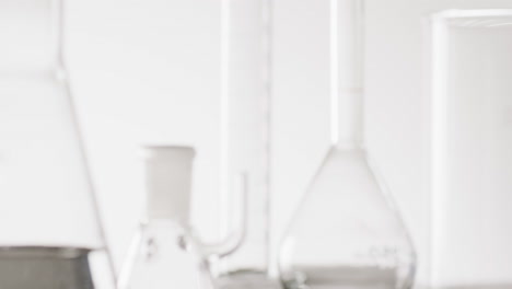 video of close up of glass laboratory beakers and dishes with copy space on white background