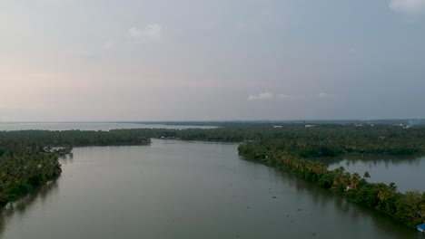 beautiful aerial shot of a backwater canal, sunset,coconut trees ,water transportation,clouds,blue sky