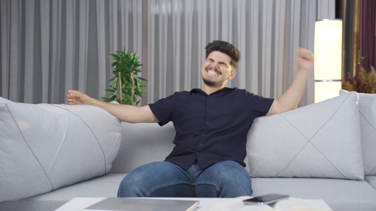 Joven alegre saltando felizmente en el sofá