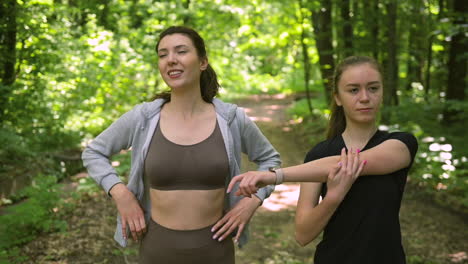 Two-Pretty-Girl-Runners-Warming-Up-And-Start-Running-In-The-Woods