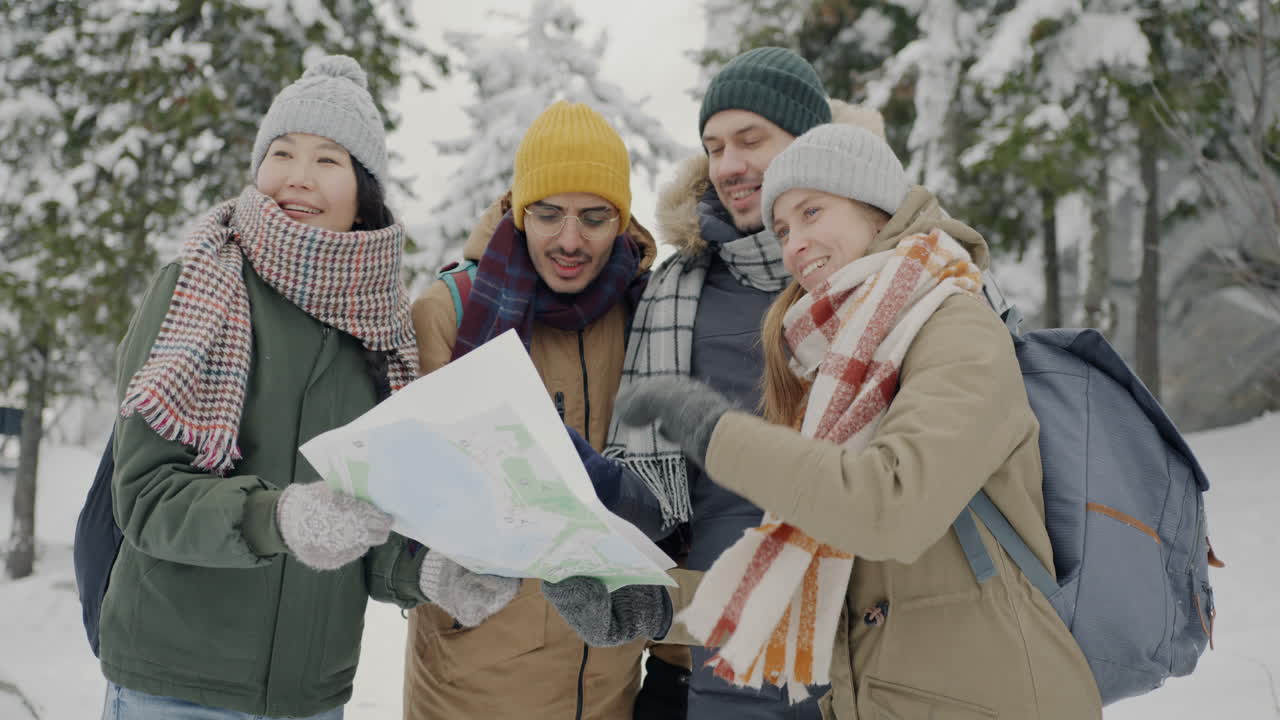 Friends Looking at a Map in a Snowy Forest