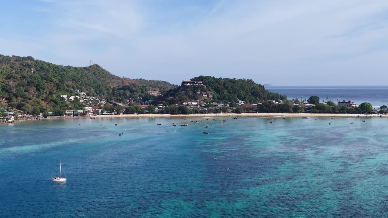 Ampia ripresa aerea di acqua turchese, isole tropicali e barche sotto un cielo blu chiaro
