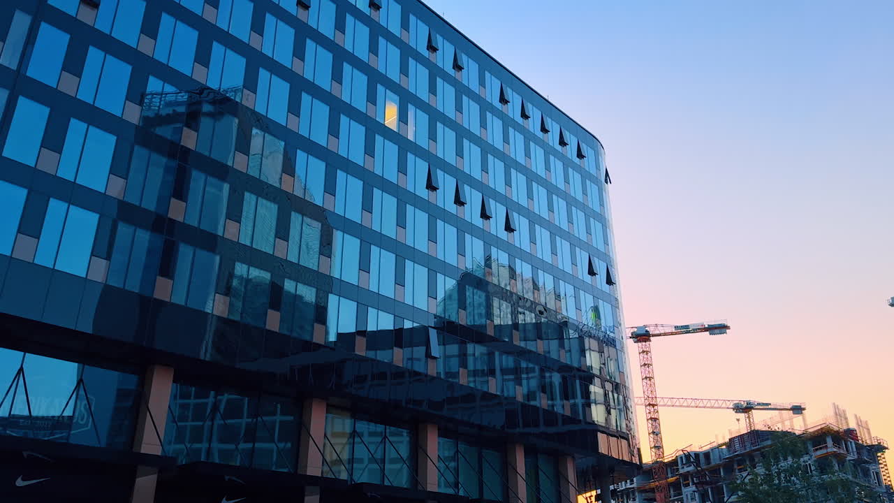 Sunset urban architecture. Sunset reflects on modern buildings as cranes work in the background, shaping a vibrant cityscape