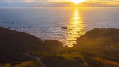 aerial sweeping time-lapse of the sun setting over the pacific ocean, showing the coastal countryside on the island of chiloe, beautiful sunset