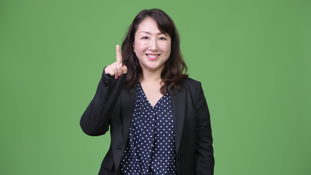 성숙하고 아름다운 아시아 사업가 여성이 손가락을 높이 가리키고 있습니다.