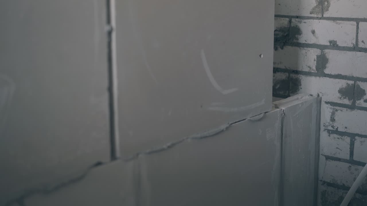 노동자 는 회색 벽 건설 에 석면 판 을 놓는다