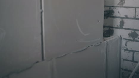 el trabajador pone placas de yeso en la construcción de la pared gris