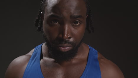 retrato en primer plano de un boxeador masculino serio con chaleco caminando hacia la cámara y en enfoque de entrenamiento para un evento deportivo contra fondo de estudio negro 3