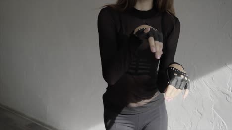 mujer con camiseta de malla negra y guantes clavados