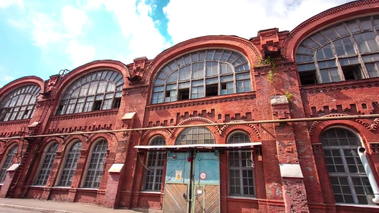 Timelapse hyperlapse di un vecchio edificio industriale in mattoni con finestre e cancelli. Vista frontale di un edificio storico in un'area industriale di un grande stabilimento.