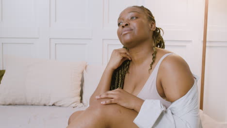 african american relaxed woman sitting on the bed and caressing gently her neck