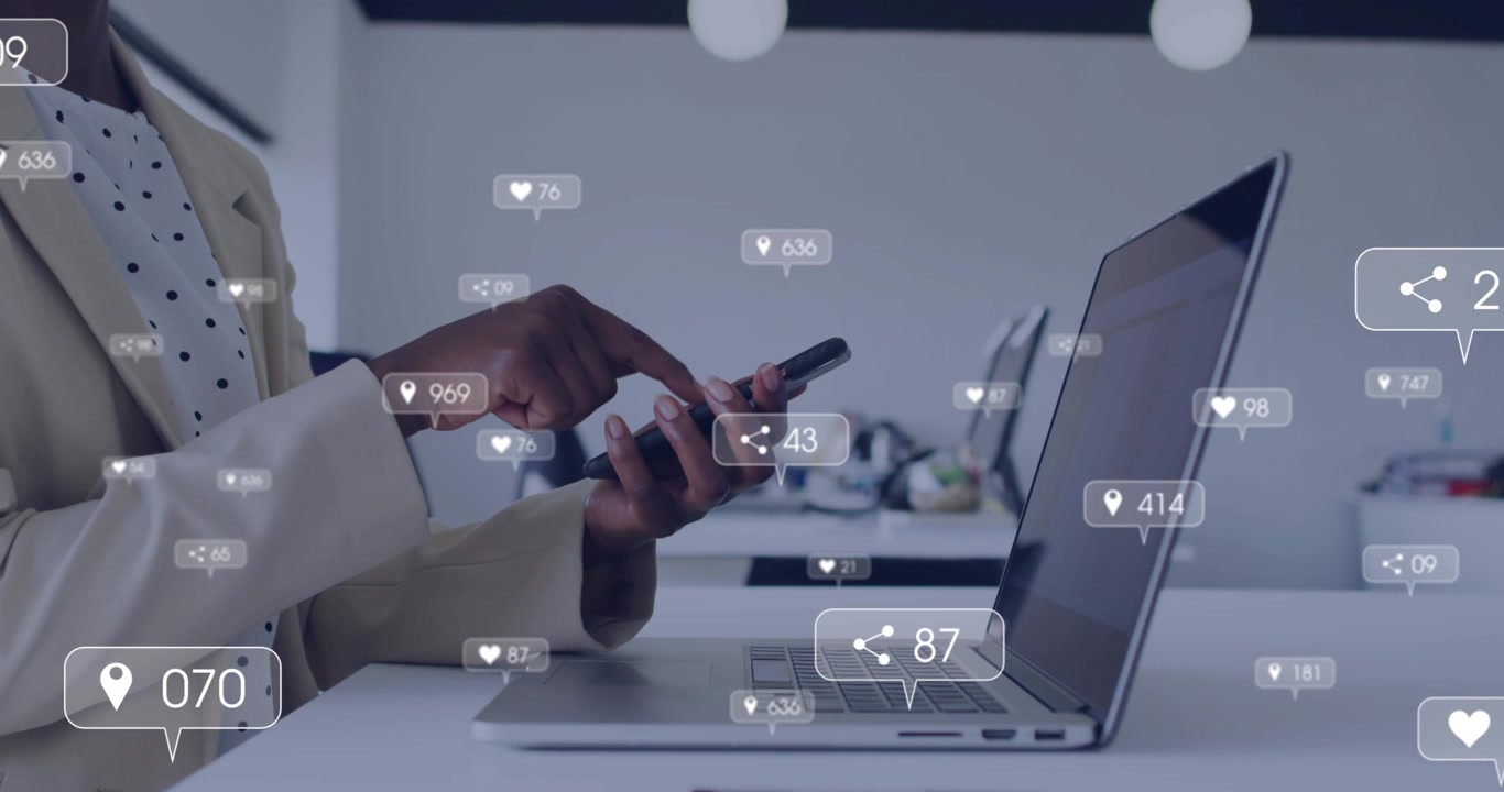 Woman tapping phone by laptop, monitoring social media engagement with animated hearts rising