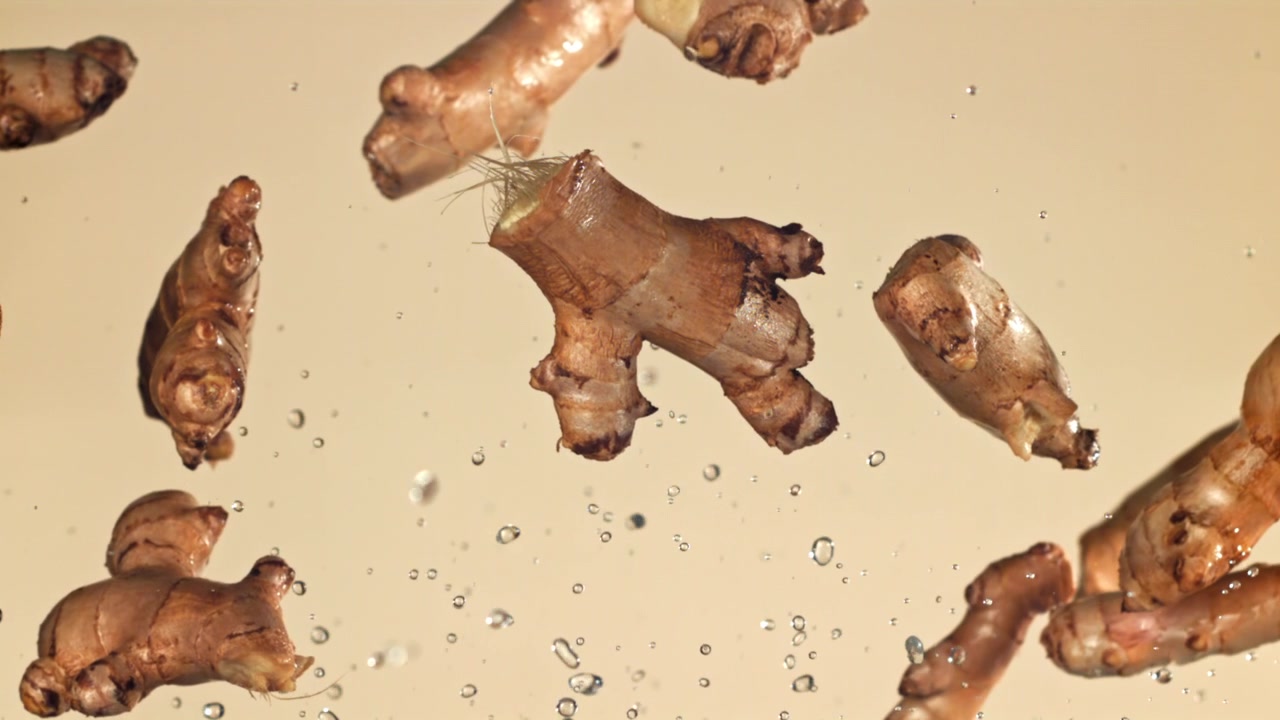 Fresh Ginger Roots Falling and Floating in Water with Splashes