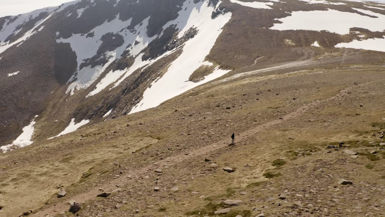 la montaña de escocia cubierta de nieve disparada por un dron revelada con una persona caminando