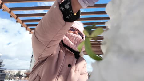 person in pink winter gear interacting with snow