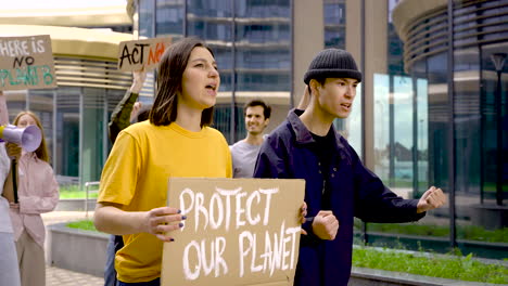 woman and man holding protect our planet placard on a protest