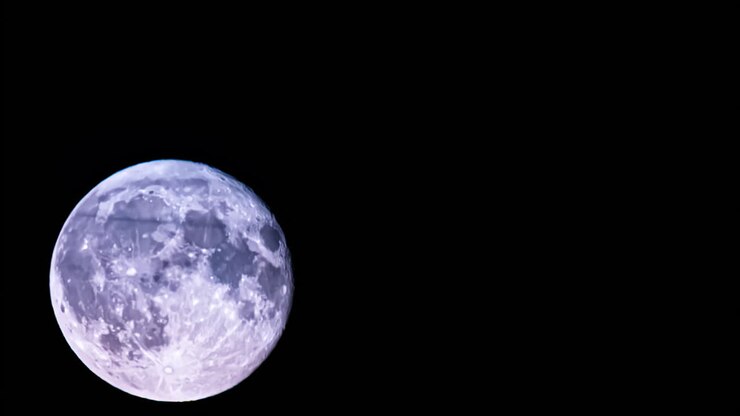 Lua cheia brilhante no céu noturno claro, dominando a escuridão com uma vista nítida de crateras e vales sombrios, com marcas por todo o corpo celeste.